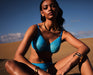 Model wearing Gossard Glossies Sheer Bra Atomic Blue in a desert setting, showcasing its lightweight, seamless plunge design and bold blue color.
